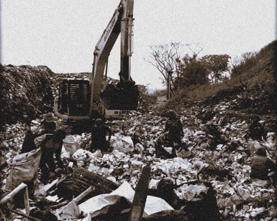 Unseen, Unannounced Excavator on a landfill pile with people scavenging through trash and debris.